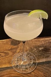 a clean and crisp gimlet served in a coupe glass with a lime wedge on the rim